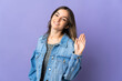 Young Romanian woman isolated on purple background saluting with hand with happy expression