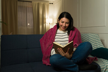 Wall Mural - Relaxed young woman reading a book on the couch