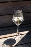 Fototapeta Mapy - objects, summer and drinks concept - close up of glass of water with flower on wooden bench