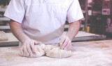 Fototapeta  - close-up on hands of baker in bakery kneading dough to bake fresh bread in the morning