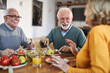 © Goran - Group of happy mature friends talking while having a meal at dining table.
