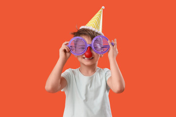 Sticker - Cute little boy with party hat and funny disguise on orange background. April Fool's Day celebration