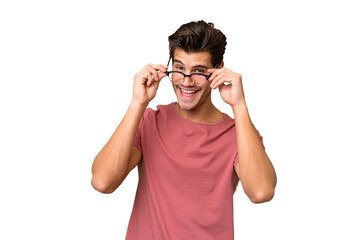 Wall Mural - Young handsome caucasian man over isolated background with glasses and surprised