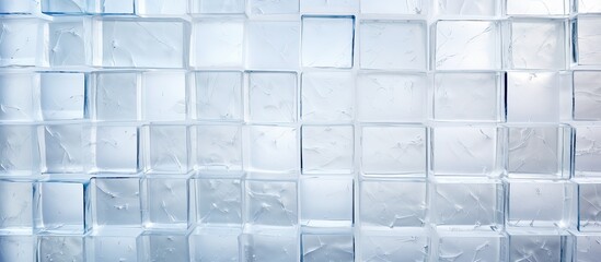 A detailed shot of a glass wall with rectangular patterned squares in shades of grey. The floorings brick pattern runs parallel to the glass, creating an electric blue font effect