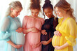 Four women in their last trimester of pregnancy, each wearing a different colored maternity dress adorned with polka dots. Their hands lovingly caress their bellies and their expressions are serene.