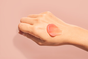 Poster - Cosmetic product lip balm or mask smudge swatch on woman hand peach background