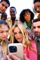 Vertical group of serious human face using mobile smiling watching something on a digital display. Technology addicted Friends looking at cell phone. They are sharing a joyful moment through gestures.