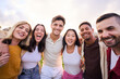 © CarlosBarquero - Bunch of happy multiracial friends having fun outdoors at the park. Diverse group of cheerful joyful young people standing up looking at the camera and smiling all together. They are hug and laugh