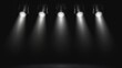 This image captures a row of stage lights beaming down onto a dark, empty stage setting an atmospheric scene