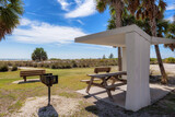 Fototapeta Sypialnia - Picnic tables and shelters at the Siesta Key Beach in Florida, where visitors can enjoy a picnic under palm trees in ocean beach.