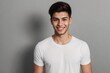 © PNG&Background Image - Young Brazilian man in a white shirt, smiling and looking at the camera, standing on a grey background with copy space.
