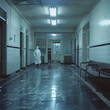 Emergency room, ghost doctor through doorway, backlit, long shot, haunting solitude.