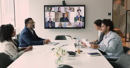 Canvas Print - Diverse business people sit at desk met in conference room engaged in videoconference with partners, share opinion, establish partnership, reporting about work sales results use video call application