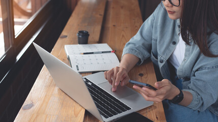 Sticker - Business woman using mobile phone and working on laptop computer at coffee shop. Student searching the information, studying online, work from cafe, distant job, business casual