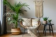 The living room has a modern and sleek design with a rattan armchair, a black coffee table, a tropical plant in a basket, a beige macrame hanging on the wall, and classy decorative items. The wall is