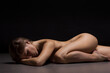 Athletic natural woman body on dark background. Nude woman Yoga.	
