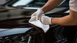 Professional auto detailer hand polishing  paint surface of a shiny black car, Car detailing, and polishing concept, a person holds the microfiber in hand and polishes the car
