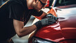 An auto detailer hand polishing the paint surface of a shiny red car, a person inspecting the paint surface for damages, Car detailing, and polishing concept