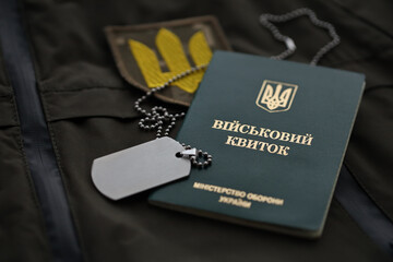 Wall Mural - Military token or army ID ticket lies on green ukrainian military uniform indoors close up