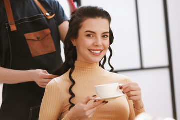 Wall Mural - Hair styling. Professional hairdresser working with smiling woman while she drinking coffee in salon, closeup. Space for text