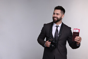 Wall Mural - Happy businessman with passport, tickets and camera on grey background. Space for text