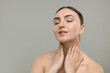© New Africa - Beautiful woman touching her neck on grey background. Space for text