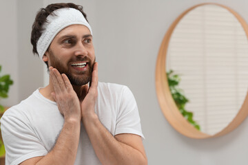 Wall Mural - Washing face. Man with headband in bathroom, space for text