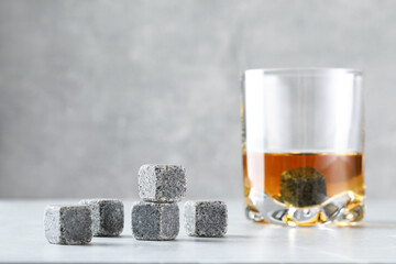 Poster - Whiskey stones and drink in glass on light table, closeup