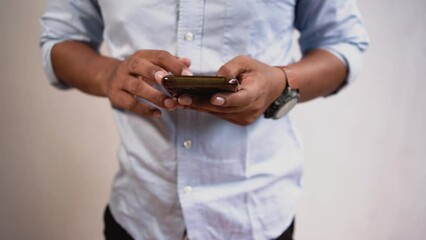 Front view an Indonesian young man using apps on a touchscreen smartphone - Concept for using technology, shopping online, using mobile apps, texting, phone addiction.