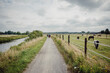 Familie radelt während einer Radreise auf einem idyllischen Radweg zwischen einem Fluss und einer Pferdewiese durch das westliche Münsterland