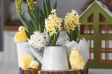 Wall Mural - Happy Easter. Spring yellow hyacinth flowers in an egg-shaped vase, chicken chicks on a white table. In the background is a white Scandinavian-style kitchen. Easter decor in the house.