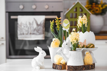 Wall Mural - Happy Easter. Spring yellow hyacinth flowers in an egg-shaped vase, chicken chicks on a white table. In the background is a white Scandinavian-style kitchen. Easter decor in the house.