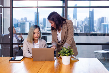 Businesswoman team leader is guiding young member to business success by showing information for goal achievement for startup and creativity project