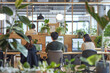 Modern office teamwork: people collaborate, communicate, A group of people are working in a cubicle with plants in the background. Scene is calm and focused, as the people are working on computers