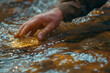 Hand of a prospector panning for gold in a river or water, discovery of gold and the increasing demand for gold