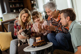 Fototapeta Tematy - Joyous Family Celebrating Grandmothers Birthday With Cake in a Cozy Living Room