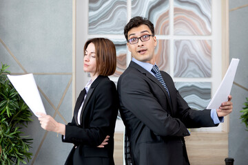 Two office workers standing with documents in the office. Business people working hard in the office. Financial and economic concept