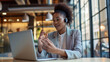 © Studio Nova - woman is engaging in a video call or virtual meeting, gesturing with her hands, with earphones in, and looking intently at the laptop screen in a modern office setting