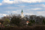 Fototapeta Kwiaty - A small church on a hill among trees against a blue sky