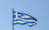 Fototapeta Paryż - National flag of Greece waves on a flagpole against blue sky
