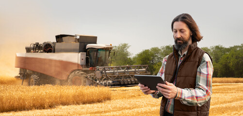 Aufkleber - Farmer with digital tablet on a background of harvester. Smart farming concept.