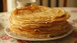 a stack of pancakes sitting on top of a white plate on top of a flowered tablecloth covered table.