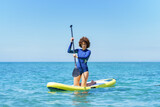 Fototapeta  - Confident woman on paddleboard in sea