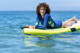 Fototapeta Tematy - Delighted female lying on SUP board in sea