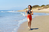 Fototapeta Tematy - Focused young sportswoman exercising on seashore in daylight
