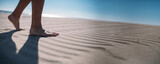 Fototapeta  - Men's bare feet on the sand. Close-up of the legs.
