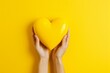 Caring Hands Holding Yellow Heart on Vibrant Yellow Background