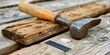 A hammer on wooden boards, its worn handle testifies to countless constructions. Board aged by time and marked by hard work with a hammer.