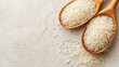 © Jafree - Grains of white rice in two wooden spoons on white textured background. Top view. Banner with copy space. Concept of cooking ingredient, healthy nutrition, cereal grain, and agricultural product.