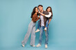 © Home-stock - Happy loving parents man, woman and their daughter standing posing isolated on blue studio background, father carrying girl on back, giving piggyback ride